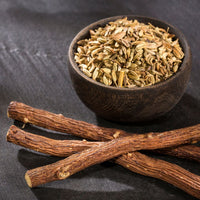 Small bowl of fennel seeds next to 3 sticks of licorice roots