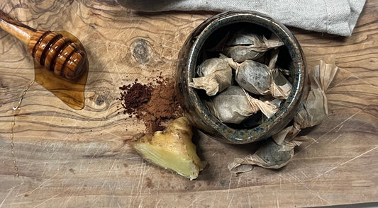 Herbal cough drops on a wooden cutting board with ginger, cinnamon, cloves and honey
