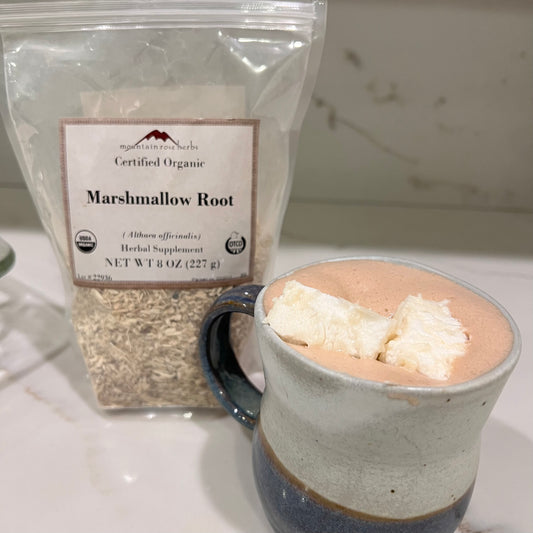 Bag of mountain rose herbs marshmallow root next to a coffee cup filled with hot chocolate with 2 squares of homemade marshmallow