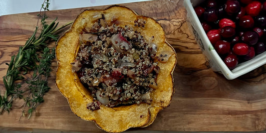 Finished acorn squash on a cutting board with herbs and cranberries