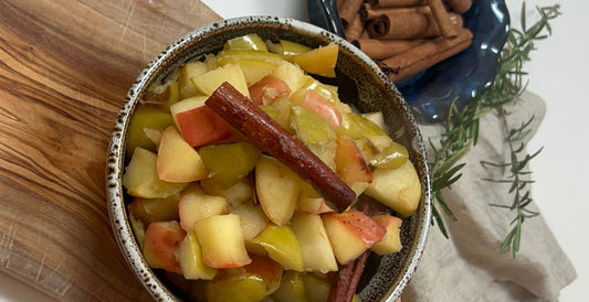 Stewed apples in a bowl, with a cinnamon stick on top