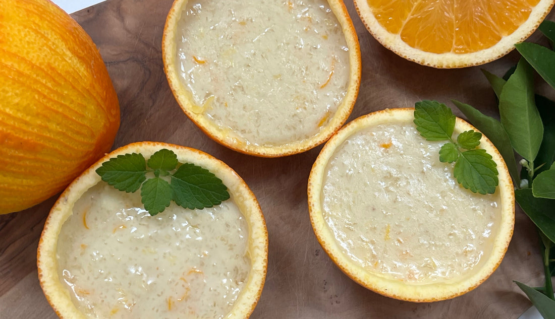 Orange pudding cups, in a an orange peel on a wooden cutting board