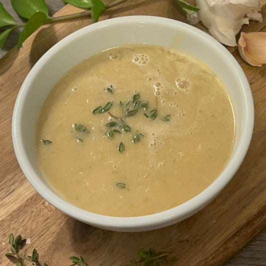 Garlic soup in a bowl with thyme on top 