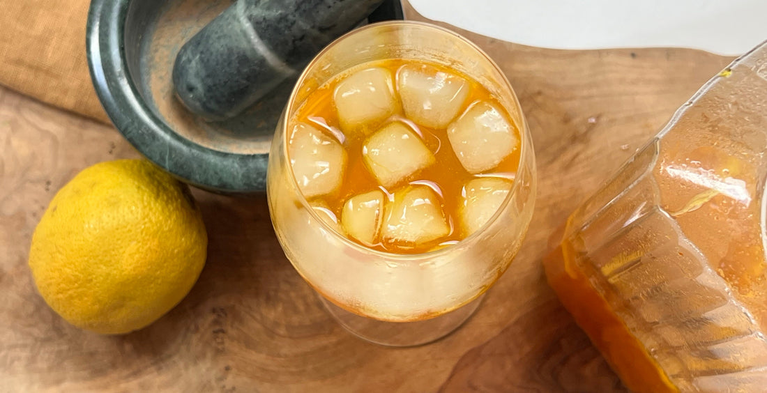 Saffron mocktail on a cutting board, with a lemon and a mortar and pestle 