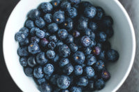 A white bowl full of blueberries.