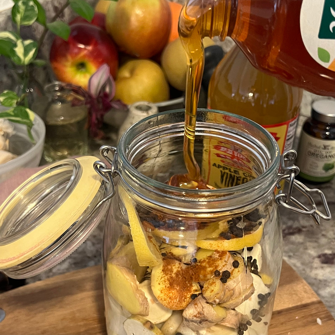 Pouring honey into a large glass jar with all chopped ingerdients 