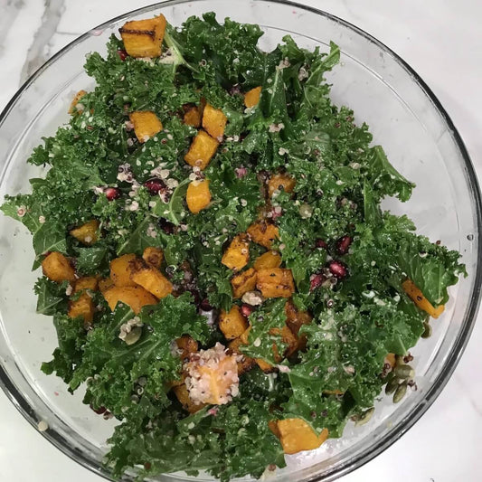 Plate of chopped kale, butternut squash, pomegranate seeds in a glass bowl  